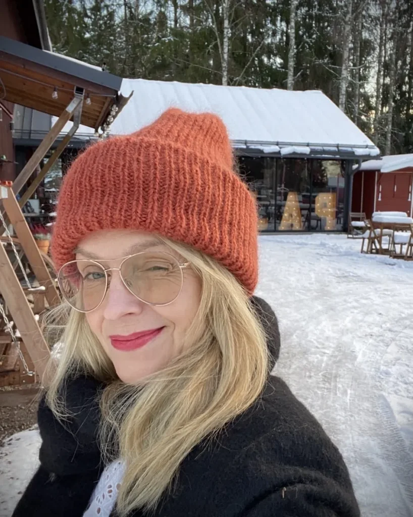 Anu Sinisalo talvisessa maisemassa punainen pipo päässä.