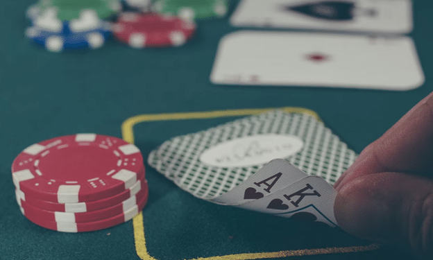 Pelaaja paljastaa korttinsa pokerimerkkien ympäröimänä